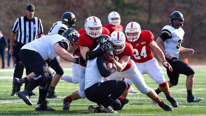 Peyton Thiry (62) and Drake Matuska (37) of St. John's University tackle St. Olaf quarterback Nate Penz during Saturday's game at Clemens Stadium in Collegeville.