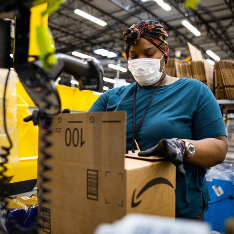 An Amazon employe wearing a face covering and glov
