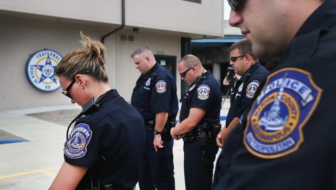Indianapolis Metropolitan Police Department officers gather for prayer at a vigil at the Indianapolis FOP Lodge, 1525 S. Shelby St., Indianapolis, during mid-shift roll call on Wednesday, July 15, 2015.