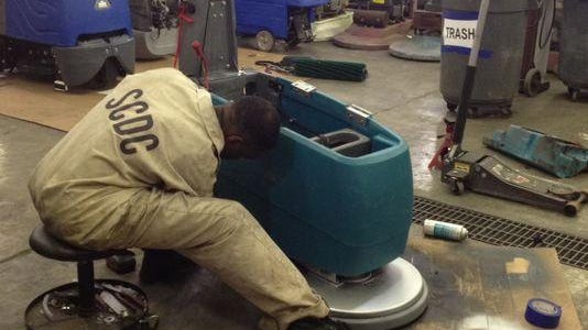 An inmate refurbishes a buffing machine while working for Southeastern Equipment, a service program.