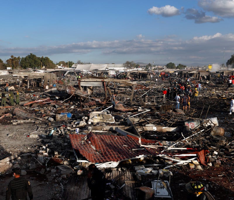 Firefighters and rescue workers walk through the scorched ground of Mexico's best-known fireworks market after an explosion explosion ripped through it, in Tultepec, Mexico, Tuesday, Dec. 20, 2016.