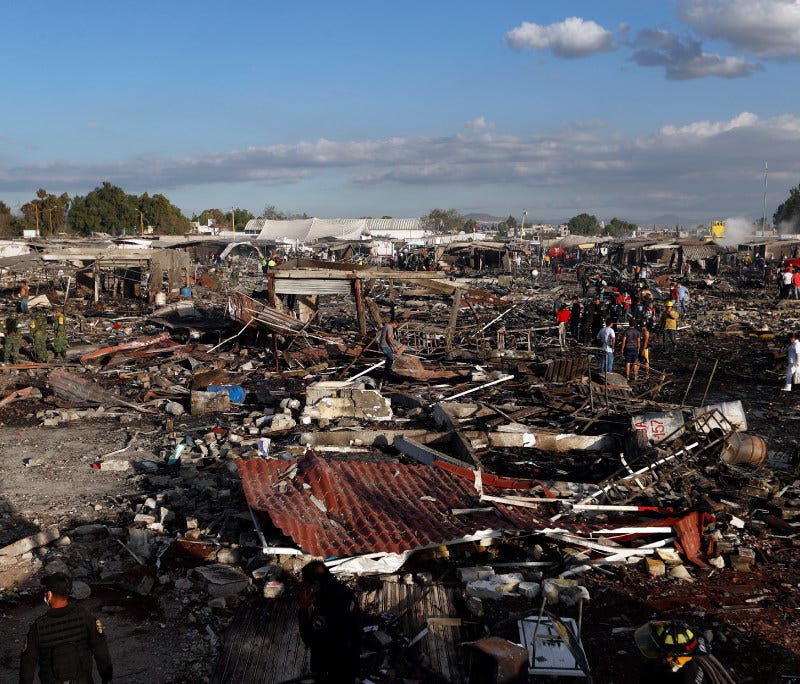 Firefighters and rescue workers walk through the scorched ground of Mexico's best-known fireworks market after an explosion explosion ripped through it, in Tultepec, Mexico, Tuesday, Dec. 20, 2016.