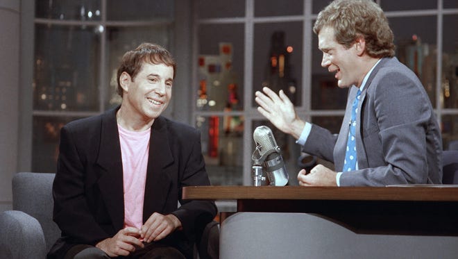 Performer Paul Simon listens to David Letterman on the set of NBC's "Late Night with David Letterman" in New York, Sept. 11, 1986. Simon was promoting his latest album "Graceland" which features African music. (AP Photo/David Bookstaver)
