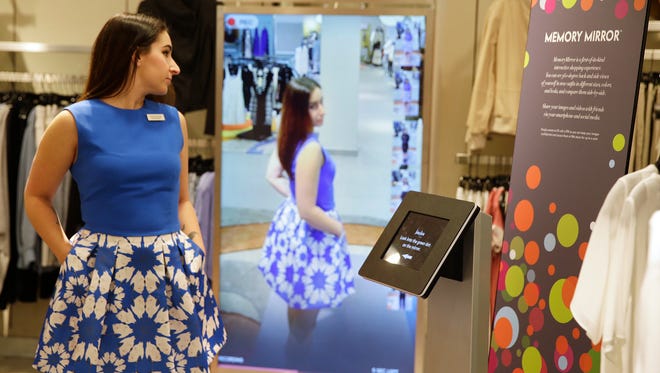 In this photo taken Wednesday, April 15, 2015, sales manager Alysa Stefani demonstrates the Memory Mirror at the Neiman Marcus store in San Francisco's Union Square. The mirror is outfitted with sensors, setting off motion-triggered changes of clothing. The mirror also doubles as a video camera, capturing a 360 degree view of what an outfit looks like and making side-by-side comparisons. (AP Photo/Eric Risberg)