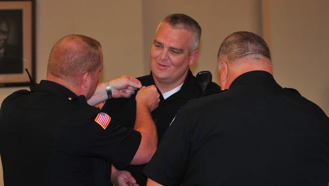 Major Jon Bales and Major Mike Britt pin insignias onto the uniform of Sgt. Austin Lipps as Lipps receives his promotion in June 2018.