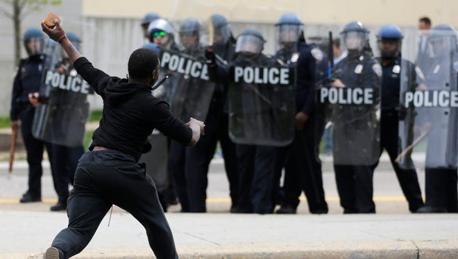 A man throws a brick at police Monday, following the funeral of Freddie Gray in Baltimore.