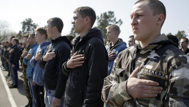 Ukrainian army recruits hold their hands over their hearts as the national anthem is played during a farewell ceremony in Kiev on April 16. About 800 conscripts were to leave Kiev to serve in the regular army but would not be sent to eastern Ukraine, according to the Ministry of Defense.