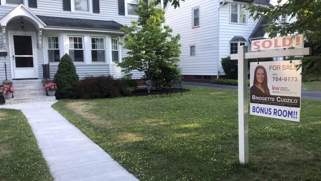 A sold sign hangs in front of a house in Brighton, N.Y. Average rates on long-term mortgages fell again this week, pushing the key 30-year loan to a record low for the eighth time this year.