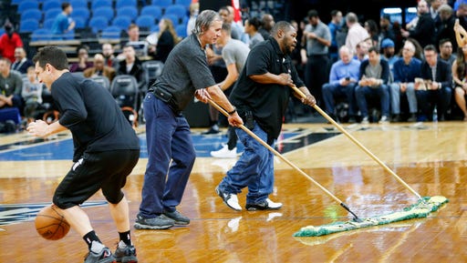 A Portland Trail Blazers player, left, practiced as Target Center workers wipe down the wet basketball floor prior to the NBA basketball game against the Minnesota Timberwolves Monday, March 6, 2017, in Minneapolis.