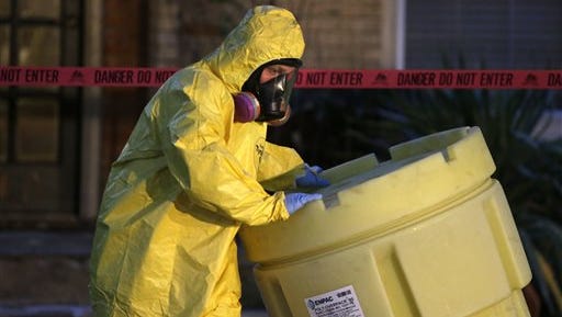 A hazmat worker moves a barrel while finishing up cleaning outside an apartment building of a hospital worker, Sunday, Oct. 12, 2014, in Dallas. The Texas health care worker, who was in full protective gear when they provided hospital care for Ebola patient Thomas Eric Duncan, who later died, has tested positive for the virus and is in stable condition, health officials said Sunday. (AP Photo/LM Otero)  