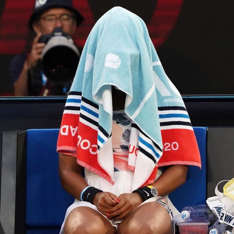 Japan's Naomi Osaka sits with her towel over her h