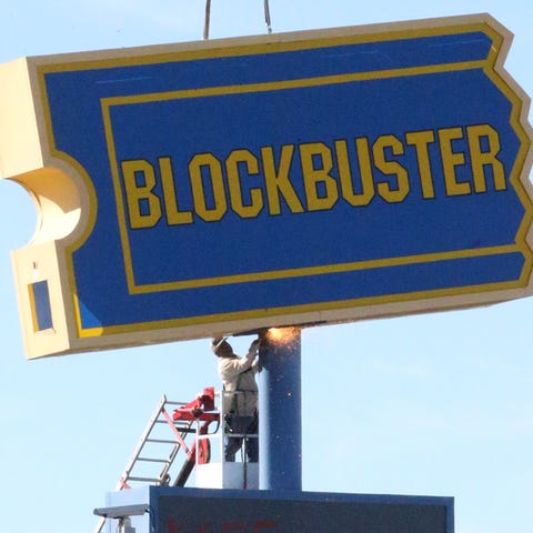 Workers prepare to remove a sign to the former Blo