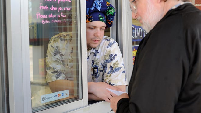One of the Fryin' Hawaiian owners, Stevie Donley, helps a customer with the menu at the restaurant on Wednesday.