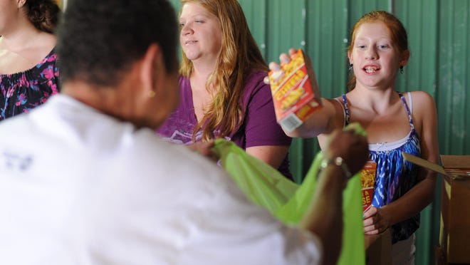 Madelyn Lewis, 11, a volunteer from Beulah Chapel Youth Group, drops a box of macaroni into a plastic bag as she and other volunteers filled Mighty Active Packs Club on Thursday at the Herlihy Moving and Storage warehouse on South Watt Street.