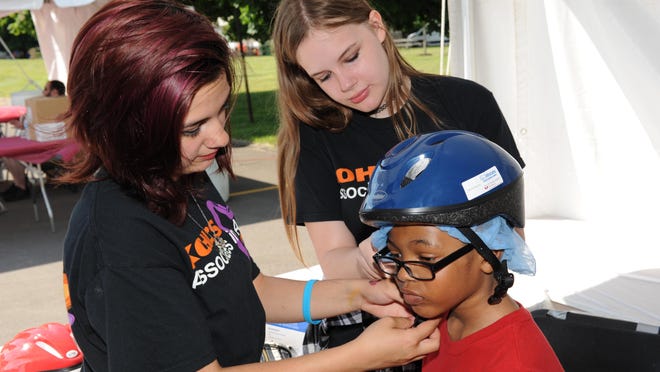 Livonia’s “Passport to Safety” offered free bike helmets as Kohl’s voulteers Izabella Bowles and Hannah Kero fit Devin Robinson with a new bike helmet.