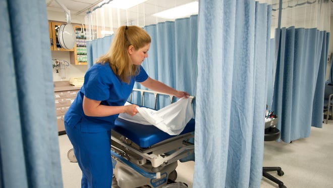 
Jennifer Peasley, staff nurse at Porter Hospital in Middlebury, changes the sheets on one of the emergency department beds. This bed, separated from other beds and patients only by a curtain, is used to accommodate acutely ill mental health patients that are brought to the emergency department.
