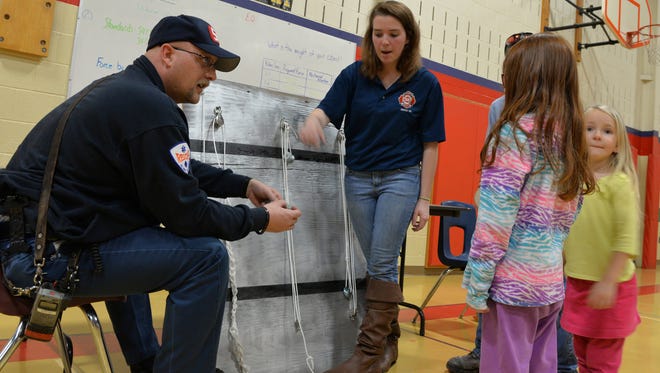 Assistant Chief Jason Weikel and firefighter Alicia Moyer of the Cleona Fire Department demonstrate how firefighters use math and engineering to complete a rescue mission using ropes and pulleys  uring the Annville Elementary School Science Technology Engineering Math on Thursday, Feb. 25, 2016. The event featured 35 stations set up by businesses and organizations to show how STEM has real world applications.