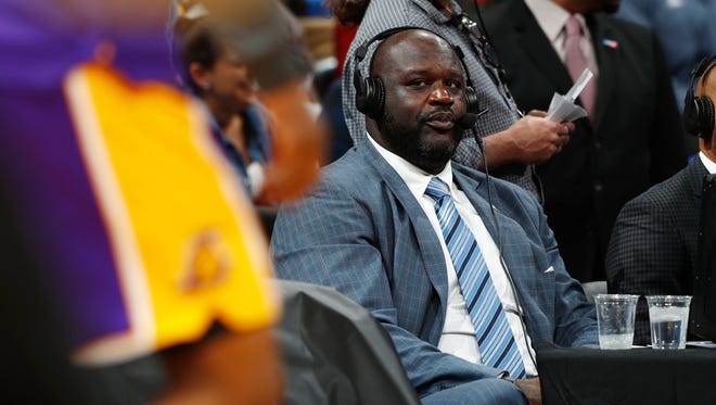 Television announcer Shaquille O'Neal, back, looks on from center court as the Los Angeles Lakers warm up to take on the Denver Nuggets in the second half of an NBA basketball game Monday, March 13, 2017, in Denver. The Nuggets won 129-101.