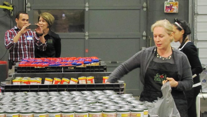 N.Y. Sen. Kirsten E. Gillibrand, D-N.Y., goes down a line of oversized containers as she fills bags Monday for the backpack program at the Food Bank of the Southern Tier warehouse in Elmira Heights.