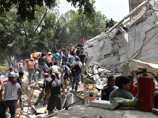 People remove debris of a collapsed building looking