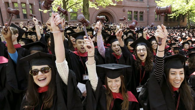 In this May 29, 2014 photo, graduates from the Harvard Law School wave gavels and cheer during Harvard University commencement ceremonies, in Cambridge, Mass.