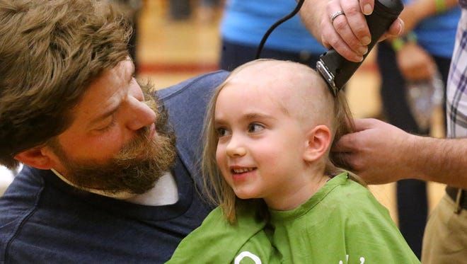Riverdale teacher Michael Shirley holds his daughter Mahayla Shirley, 6, as she shaves her head during Riverdale's 4th annual St. Baldrick's Event "Brave the Shave" Event on Friday, March 17. Mahayla Shirley raised $1,580 dollars to fight childhood cancer.