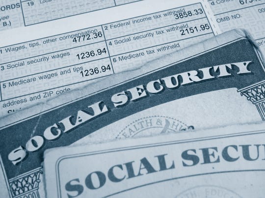 Two Social Security cards lying atop a W2 tax form, highlighting payroll taxes paid.