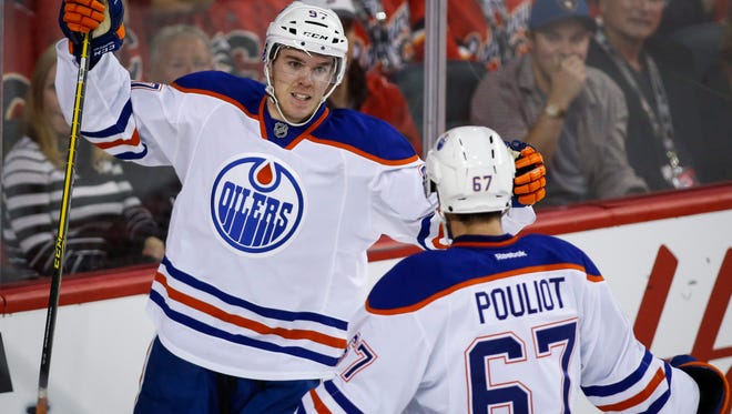 The Edmonton Oliers' Connor McDavid, left, celebrates his goal with teammate Benoit Pouliot during the second period against the Calgary Flames on Saturday, Oct. 17, 2015, in Calgary, Alberta.