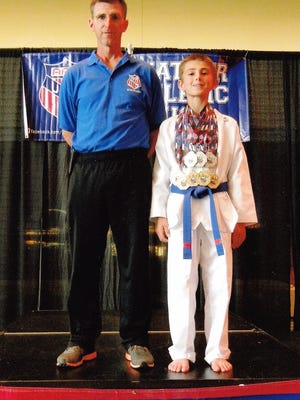 Hayden Pucker, right, wears the five gold and three silver medals he earned in competition at the the AAU Junior Olympic Games this past summer. His father Paul is at left. The Puckers are from Rosendale.