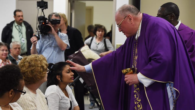 Cardinal Timothy Dolan, right, blesses Bridgette Nathan, left, of Jamaica during mass at ArchCare at Ferncliff Nursing Home and Rehabilitation Center in Rhinebeck. Nathan has Huntington's disease.