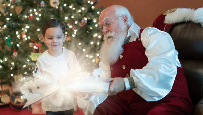 A child is enchanted with a book he's shown by Santa Max.