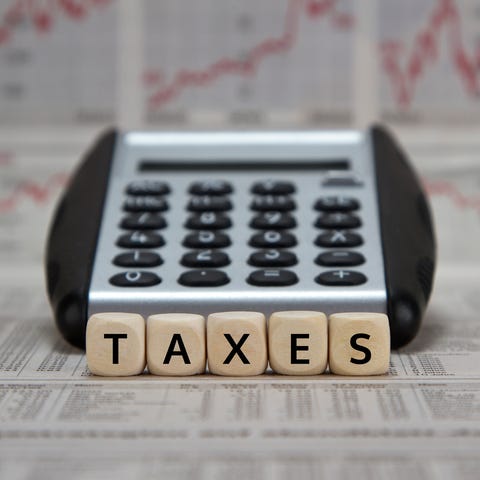 The word taxes spelled out in tiles in front of a...