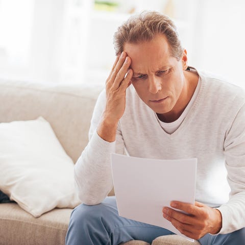 Middle-aged man reading a document and looking wor