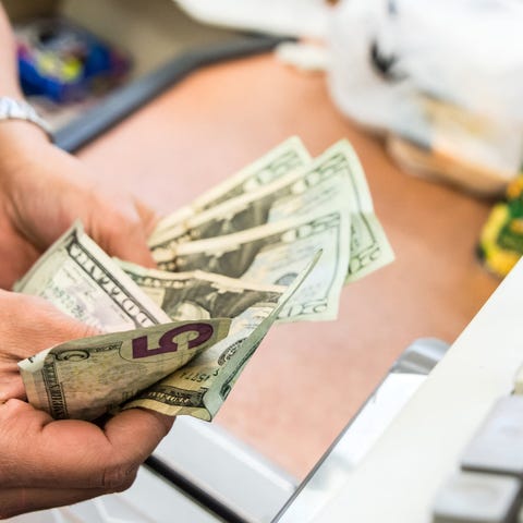 Person counting money at register.