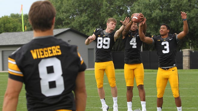 Iowa wide receivers, from left, Matt VandeBerg, Tevaun Smith and Jay Scheel go up for a catch during media day.