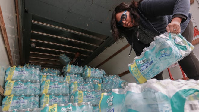 Lanice Lawso of Davison stacks some of the 300 cases of bottled water on Tuesday Oct. 13, 2015.