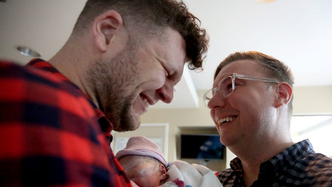 Dan, left, and Will Neville-Rehbehn, of New York City, cry while holding their son, Jackson, after Yessenia Jones, a surrogate, gave birth at OHSU Hospital in Portland, Ore., on Oct. 24, 2016.