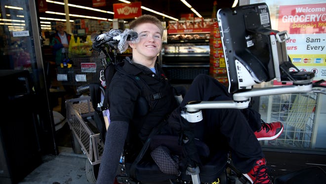 Scott Taber, 19, pulls a wagon with his wheelchair to help customers haul groceries to their cars at the Grocery Outlet on Front St. NE in Salem on Saturday, Oct. 28, 2017.