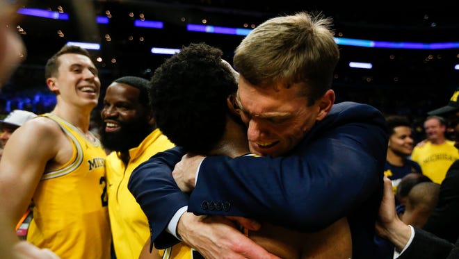 Assistant coach Luke Yaklich hugs guard Zavier Simpson after Michigan won the West Region of the NCAA tournament over Florida State in Los Angeles, Saturday, March 24, 2018.