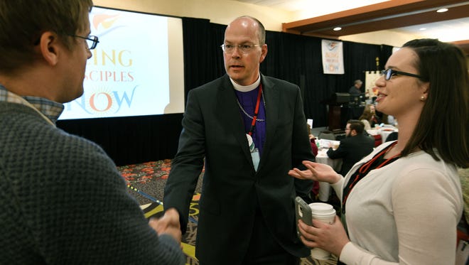 Recently installed Bishop Brian Cole, center, introduces himself to David Burman, left, and Sinead Doherty before addressing the 34th convention of the Episcopal Diocese of East Tennessee at the Holiday Inn Downtown convention hall in Knoxville on Friday, Feb. 9, 2018.