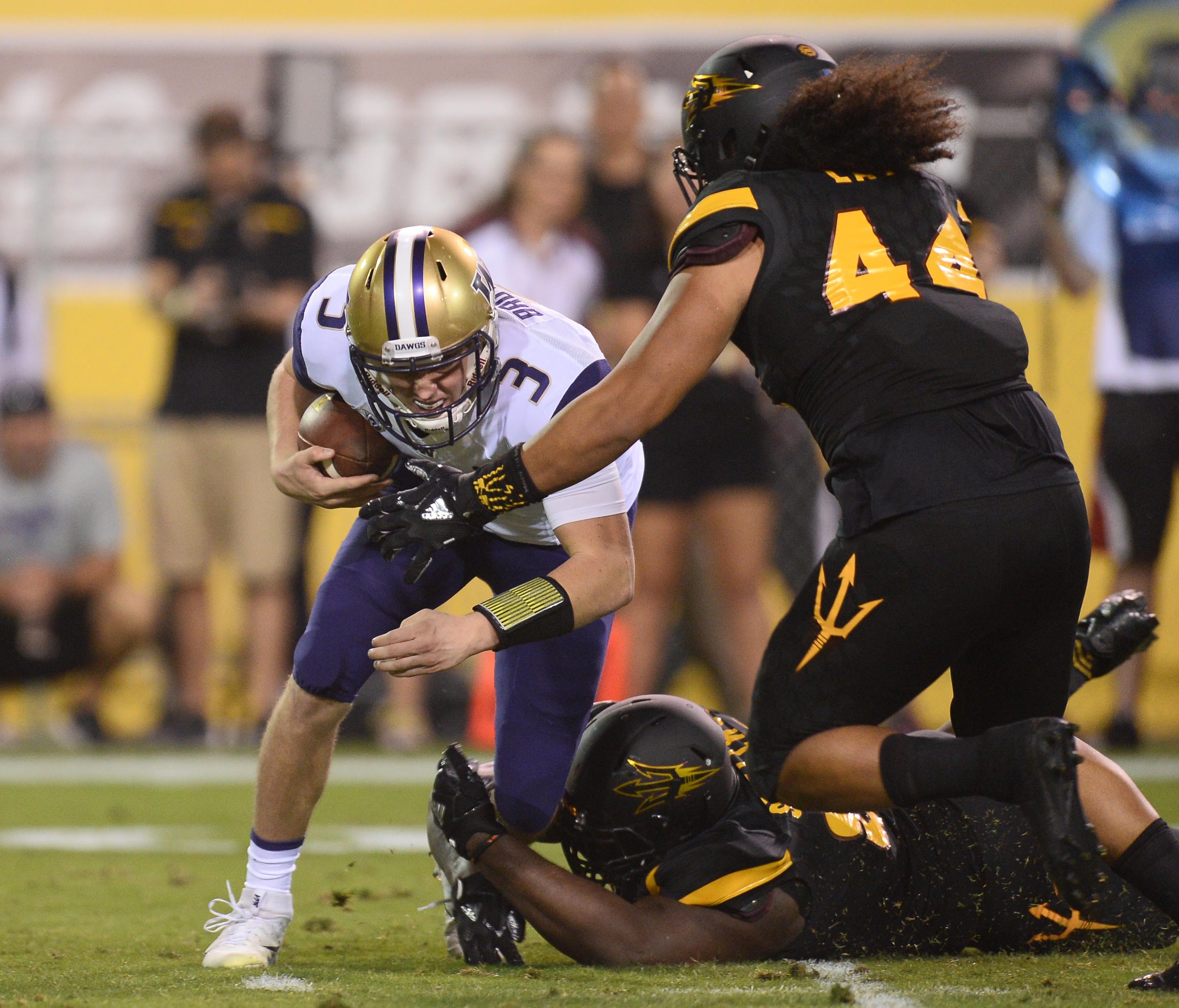 Washington Huskies quarterback Jake Browning (3) is sacked by Arizona State Sun Devils defensive lineman Tashon Smallwood (90) and linebacker Alani Latu (44) during the first half at Sun Devil Stadium.