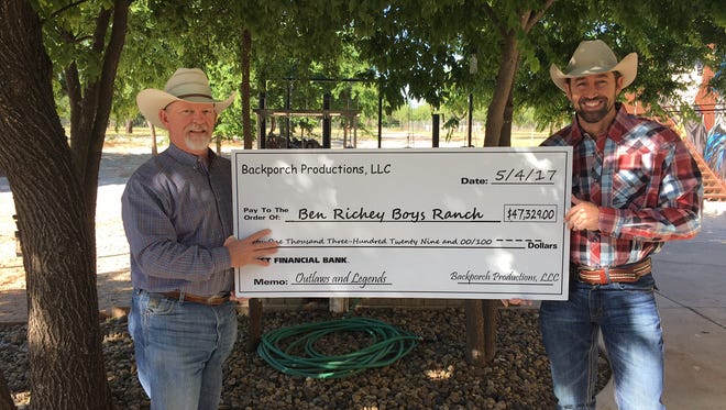 Mark Powell (right), co-owner of Backporch Productions, presents a $47,329 donation to Kerry Fortune, president of the Ben Richey Boys Ranch & Family Program. The donation was funded from proceeds from this year's Outlaws & Legends event.