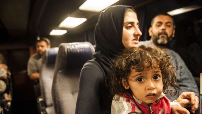 A migrant woman holds her child as they sit in a bus heading to Belgrade from the southern Serbian town of Presevo on Wednesday. The European Union unveiled plans to take 160,000 refugees from overstretched border states, as the United States said it would accept more Syrians to ease the pressure from the worst migration crisis since World War II.
