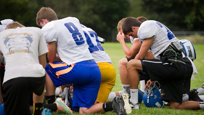 Player John Eberhart (right) and teammates bow their heads as Head Coach Mike Watkins leads a moment of silence at the end of football practice at John Carroll High School in Fort Pierce Aug. 14, 2014. The team prayed for Sebastian River High School football player William Shogran Jr., 14, his teammates and family after Shogran died  at football training camp.


CQ:Mike Watkins, William Shogran Jr.
DATE TAKEN:8/14/14