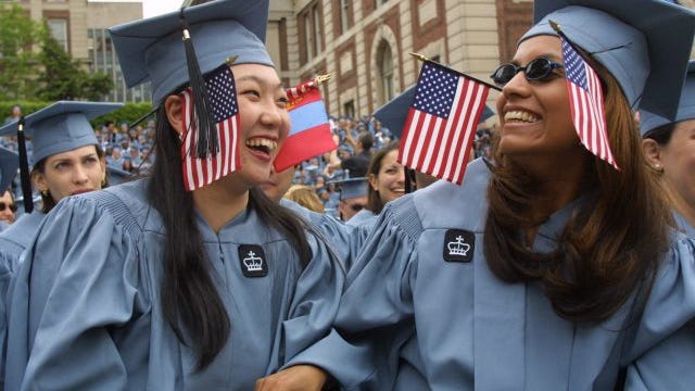 Columbia University undergraduate Tsolmon Tsatsralt, left, wears a flag from her native Mongolia as well as a United States flag, while Marina Henriquez, originally from El Salvador, also sports the Stars and Stripes during commencement exercises at the school Wednesday, May 16, 2001, in New York.