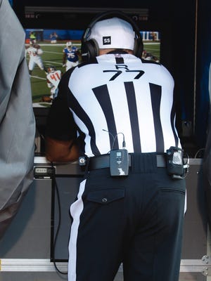 An NFL referee looks over a replay review during a game in 2014.