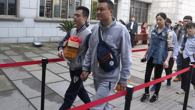 Sun Wenlin, left, and his partner Hu Mingliang hold hands as they arrive at the Furong District Court to argue in China's first gay marriage case in Changsha in central China's Hunan province on Wednesday, April 13, 2016.  A judge on Wednesday ruled against the gay couple in China's first same-sex marriage case that attracted several hundred cheering supporters to the courthouse and was seen as a landmark moment for the country's emerging LGBT rights movement.