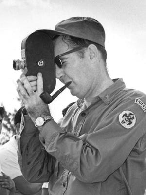 In this Pacific Daily News file photo dated Aug. 15, 1965, Louis Brouillard is shown filming footage in an outdoor setting. In the full frame of the picture, which is cropped, boys, some in Boy Scouts uniforms, stand around Brouillard.