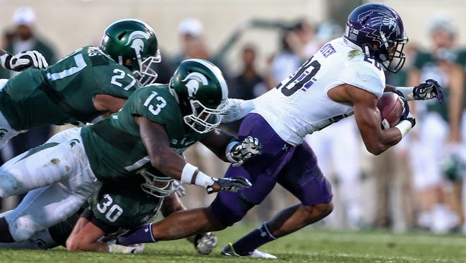 Northwestern running back John Moten IV, right, is dragged down by Michigan State cornerback Vayante Copeland (13) during the second half Oct. 15, 2016.