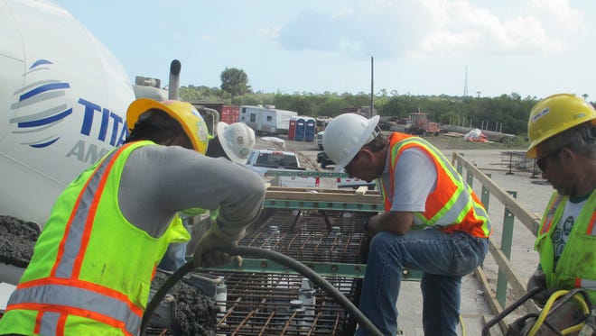 Workers pour concrete at the site of the Crosstown Parkway Extension Project.